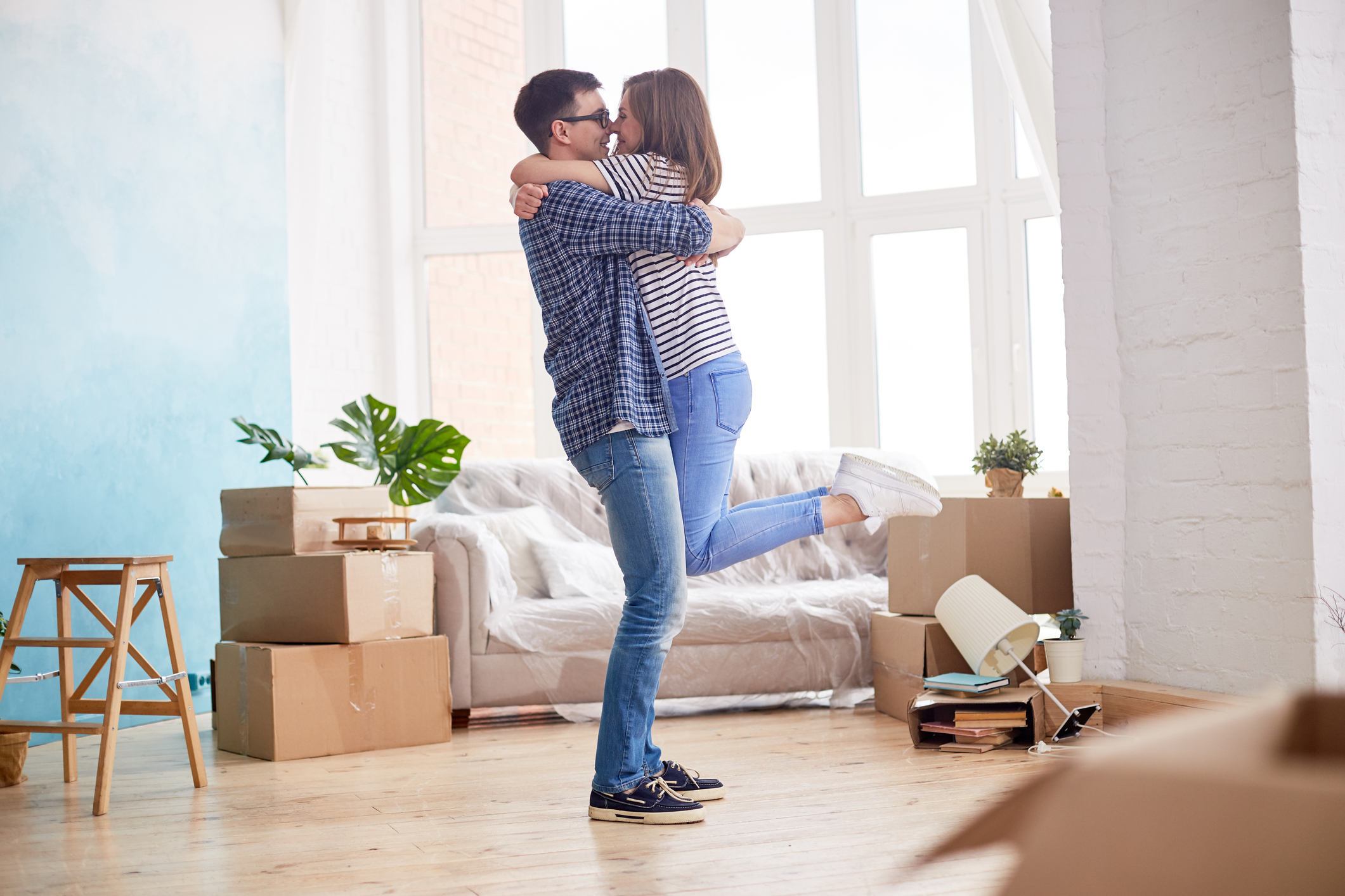 Checkliste für die Zeit nach dem Umzug Junges Paar umarmt sich zwischen Umzugskartons