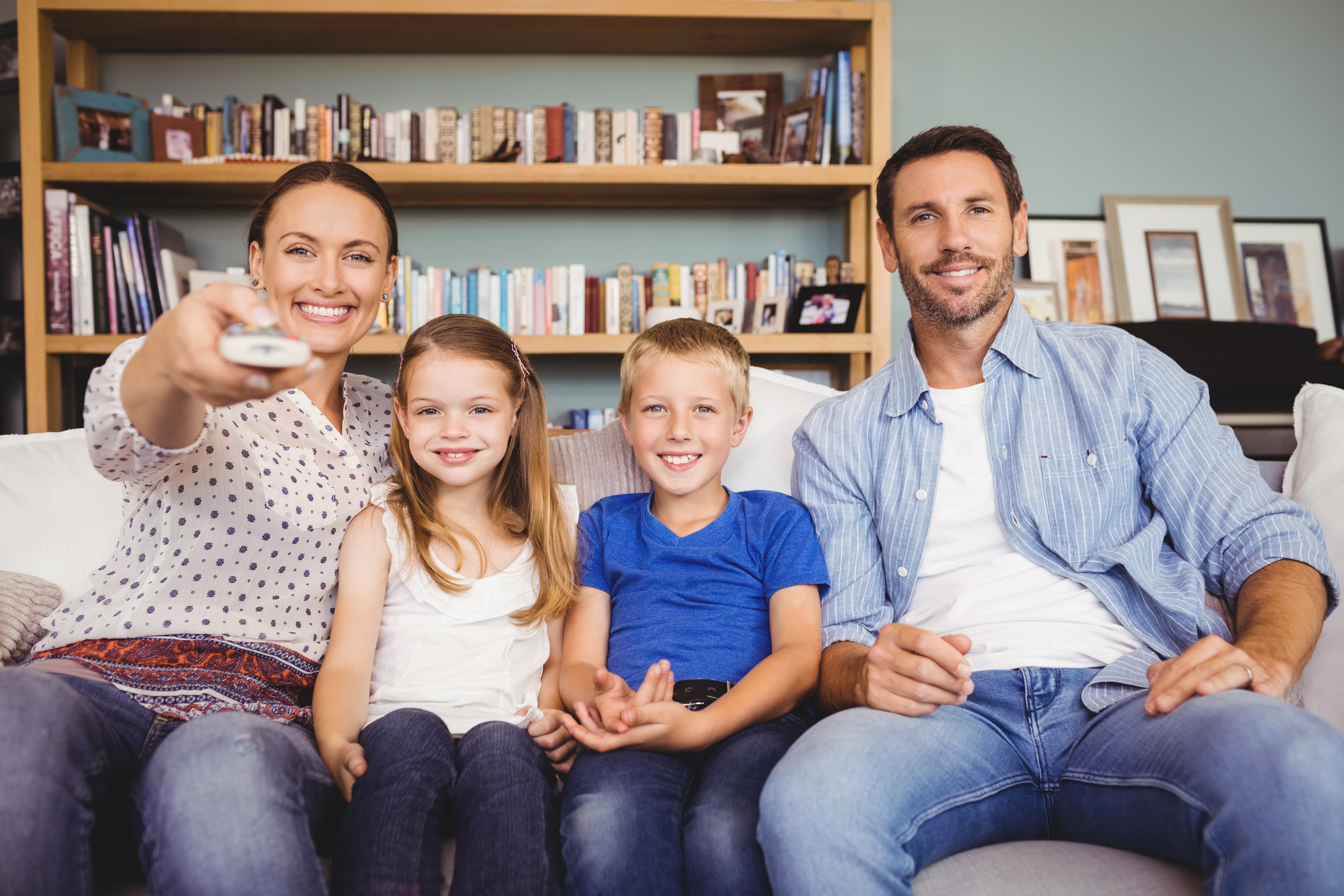 Rundfunkbeitrag nach Umzug: Eltern mit zwei Kindern sitzen auf dem Sofa und sehen fern Rundfunkbeitrag nach Umzug: Eltern mit zwei Kindern sitzen auf dem Sofa und sehen fern