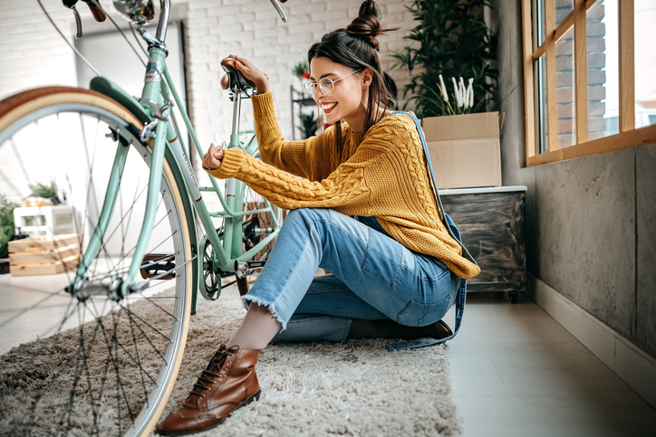 Fahrrad richtig transportieren: So klappt der Umzug Junge Frau mit Fahrrad in neuer Wohnung