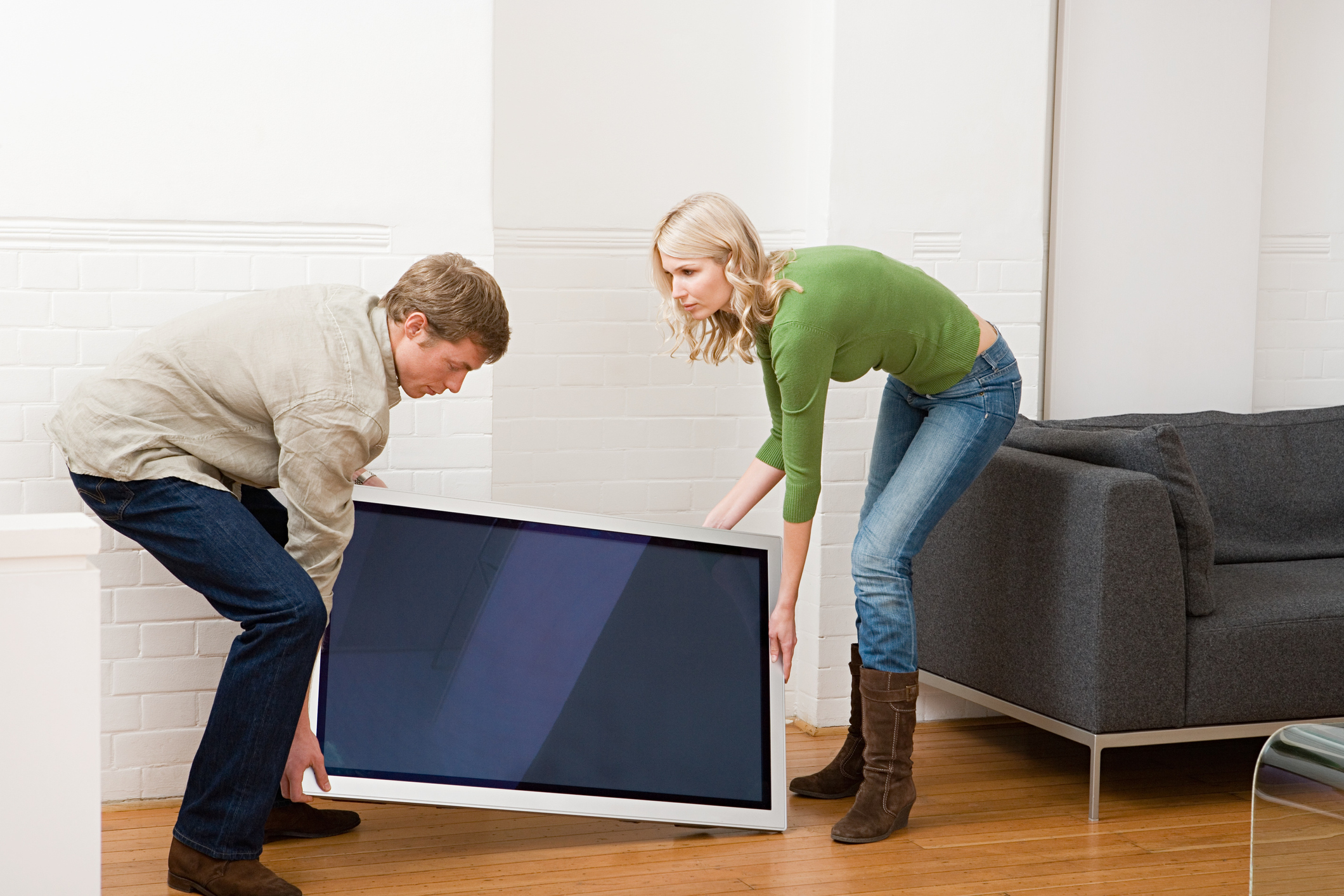 Fernseher transportieren: LED, LCD & Plasma – liegend oder stehend? Mann und Frau tragen einen Fernseher