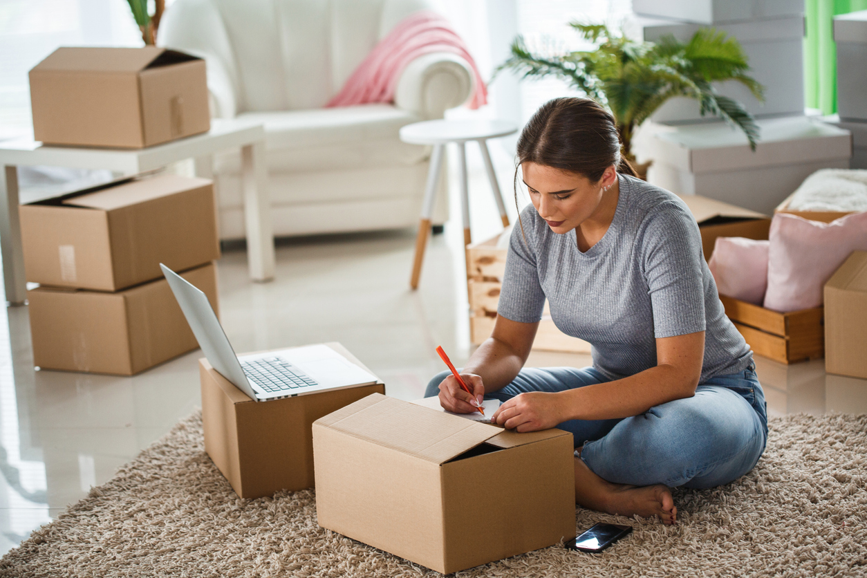 Frau sitzt zwischen Umzugskisten