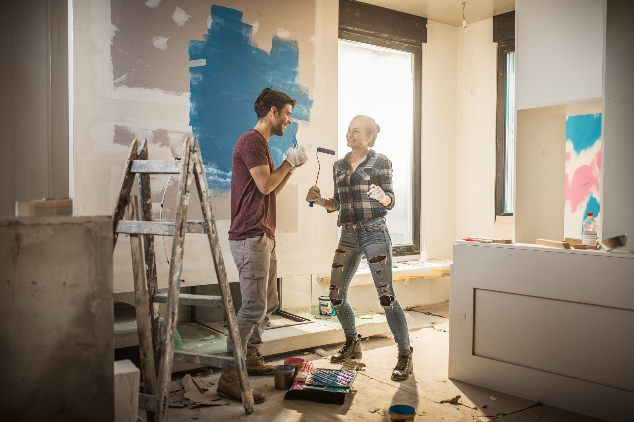 Wände streichen: Tipps und Techniken für die Wohnung Glückliches Paar streicht Wände in der neuen Wohnung