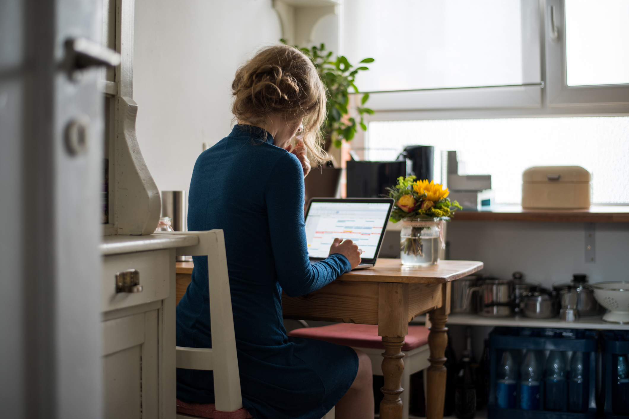 Internetanbieter wechseln: So klappt die Kündigung bei Umzug Junge Frau sitzt am Schreibtisch und arbeitet am Laptop
