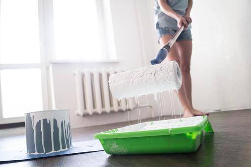 WG-Zimmer einrichten: Mehr Stauraum für Studenten Frau mit Pinselrolle und weißer Farbe