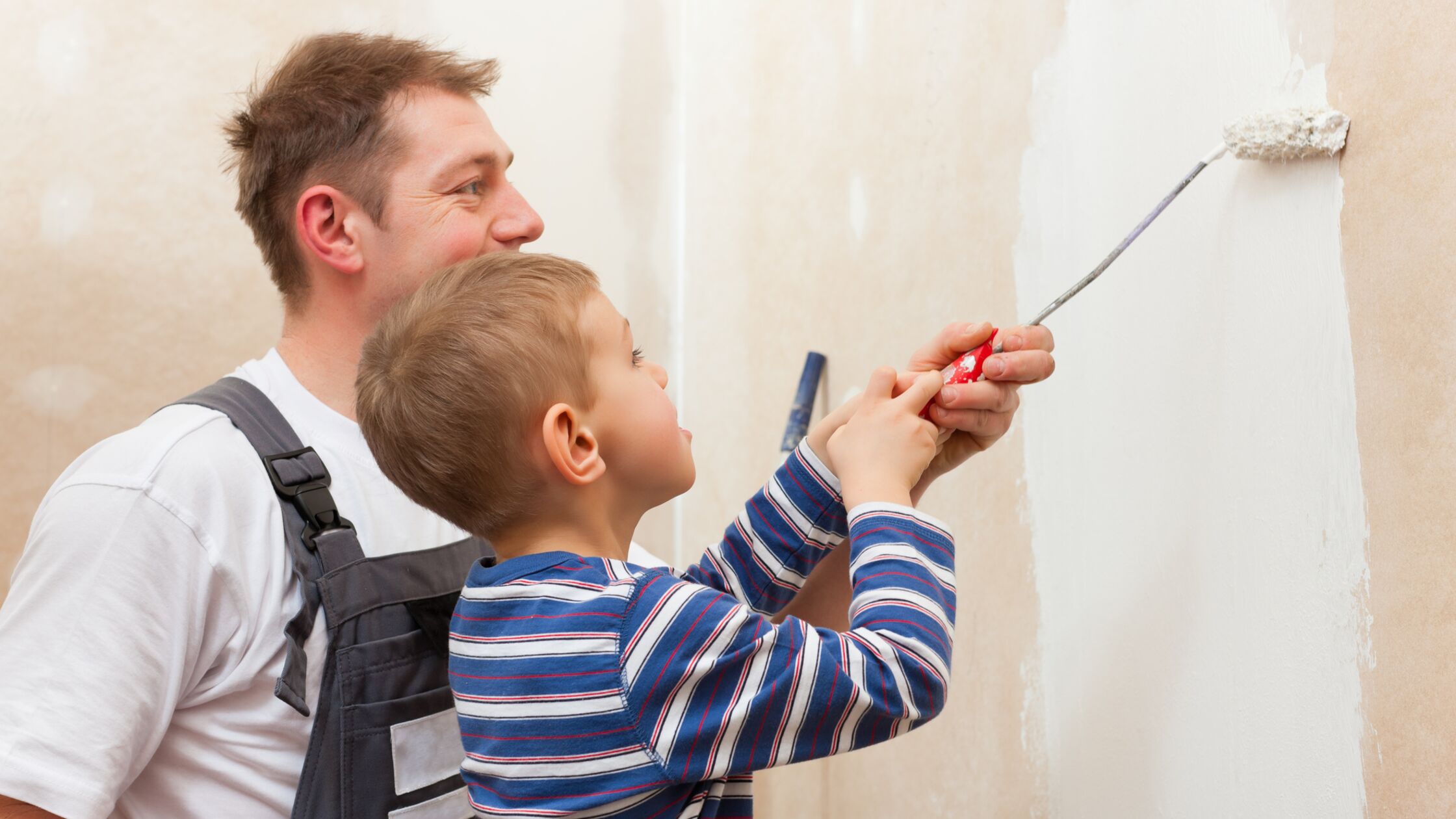 Schönheitsreparaturen: Ein Mann und ein junge streichen gemeinsam eine Wand.