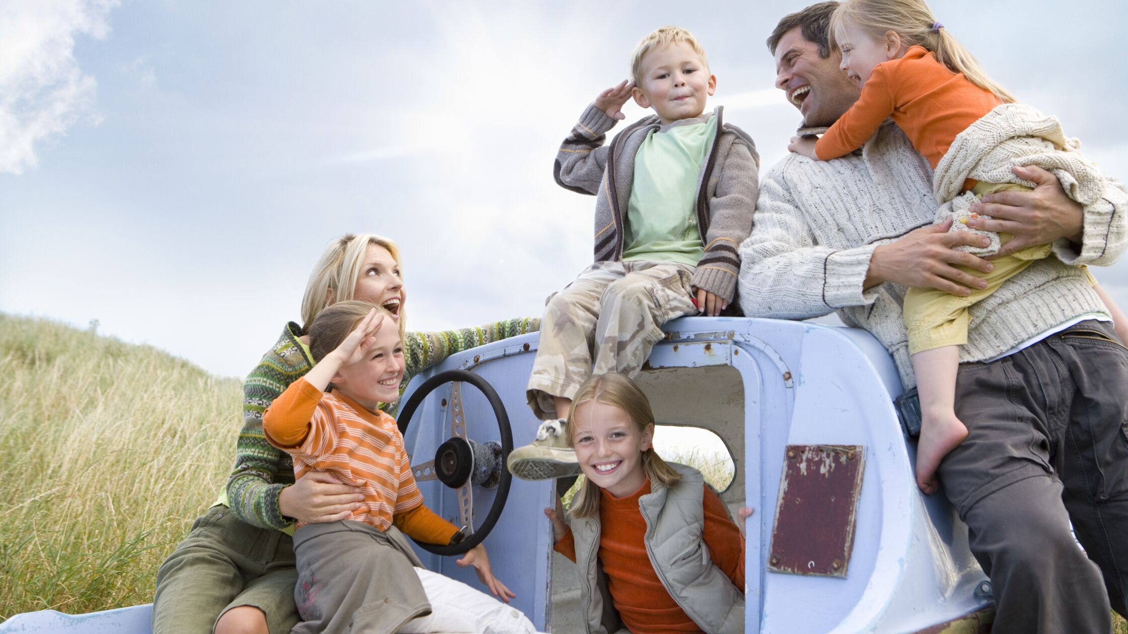Familie mit Eltern und vier Kindern lächelnd auf Boot.