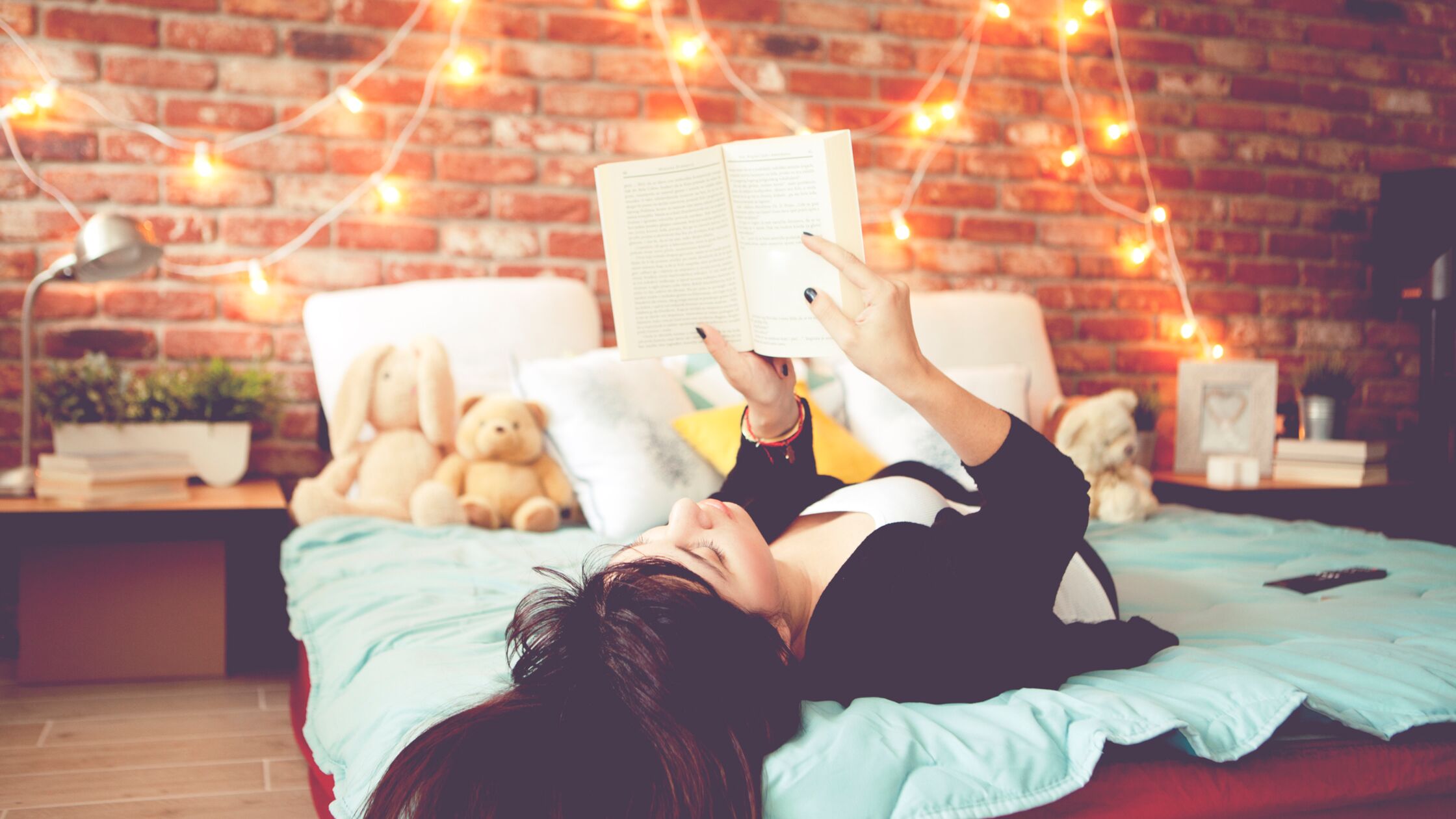 Frau liegt auf einem Jugendzimmer-Bett und liest