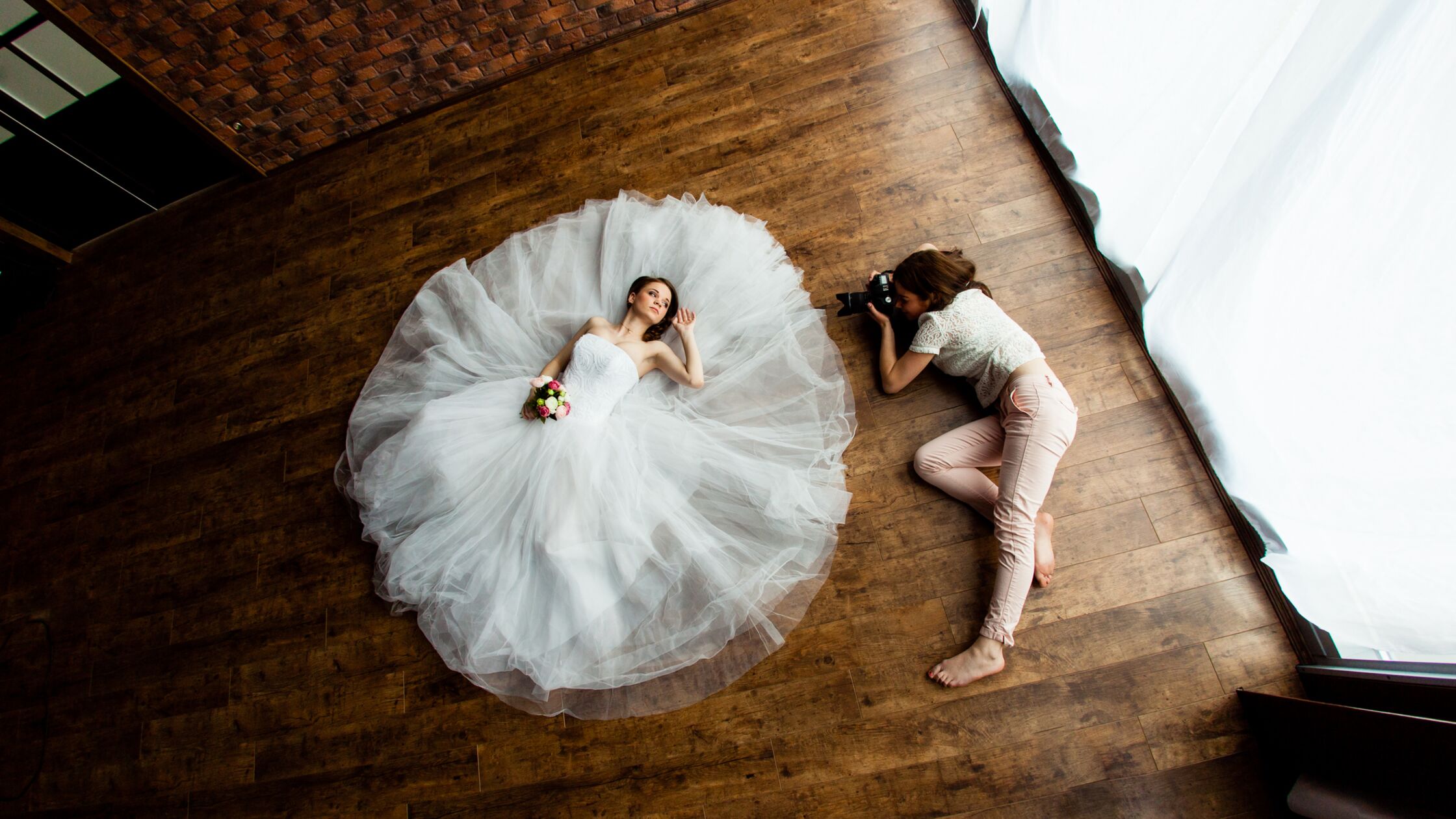Fotografin und und Model beim Brautshooting auf dem Fußboden in einer leeren Wohnung