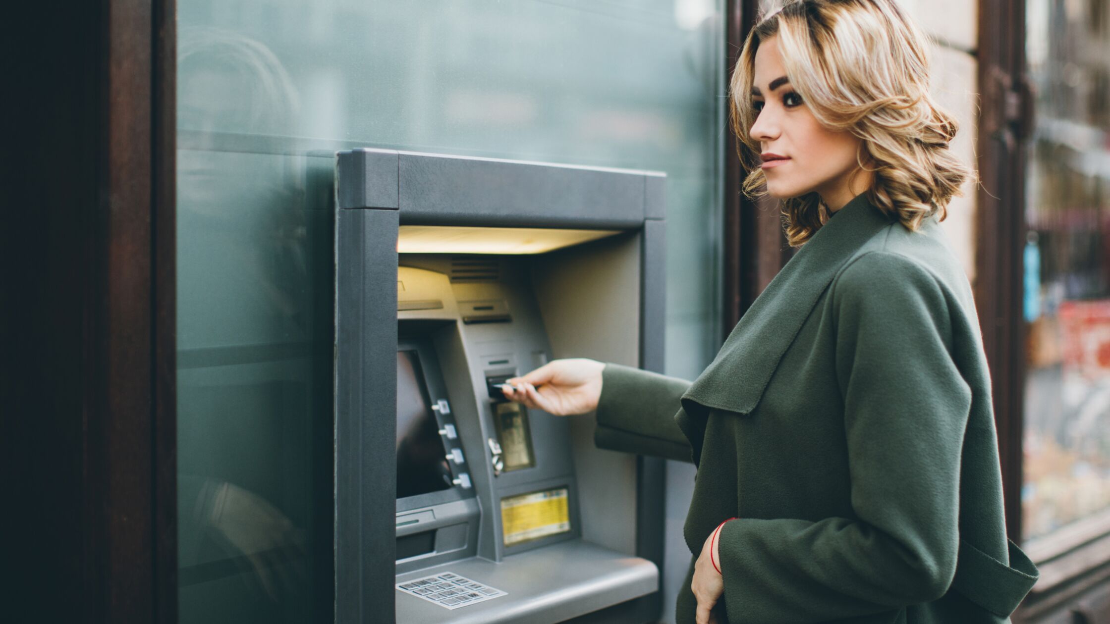 Frau steht am Geldautomaten