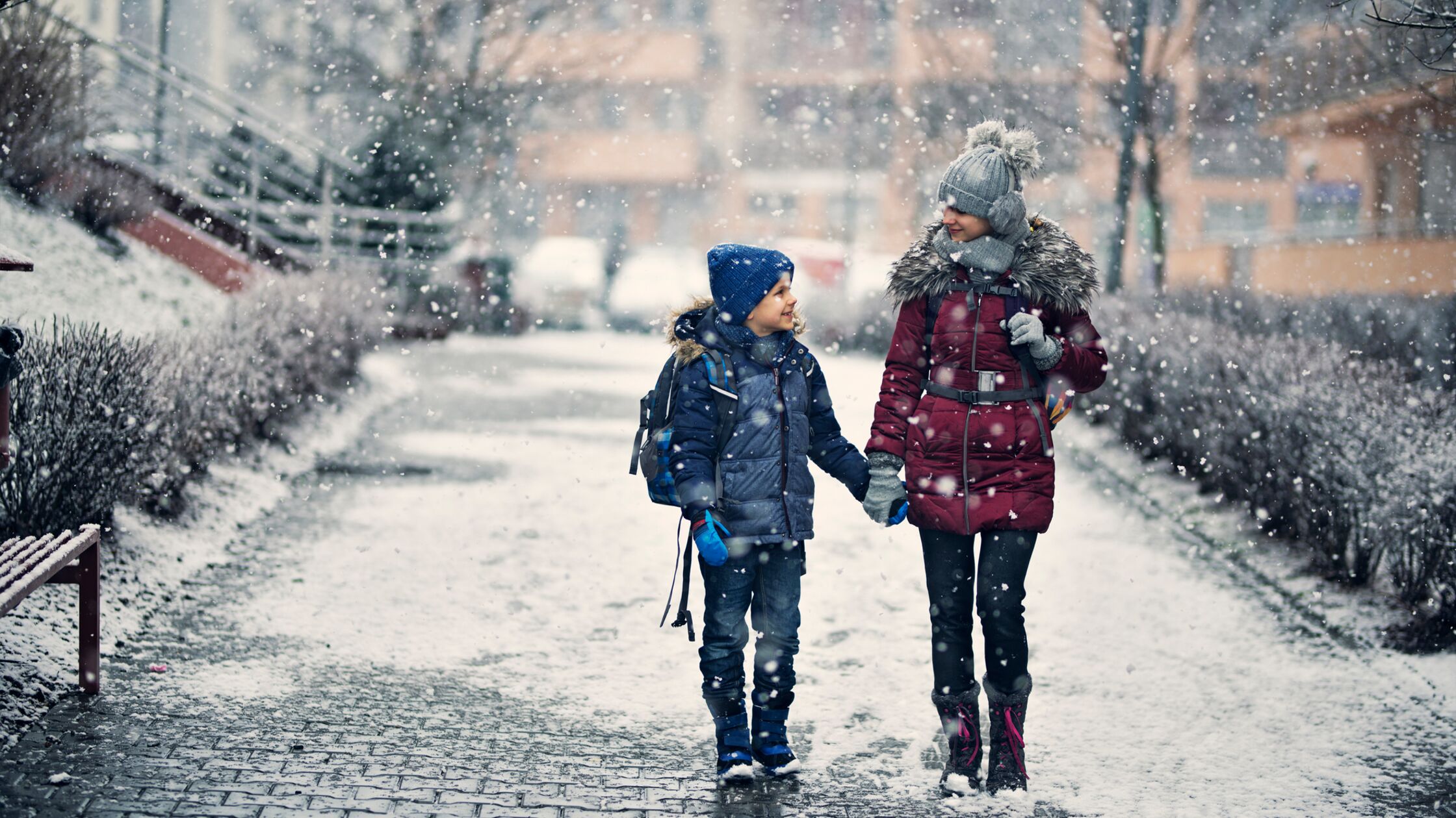 Geschwisterpaar spaziert im Winter über geräumten Gehweg
