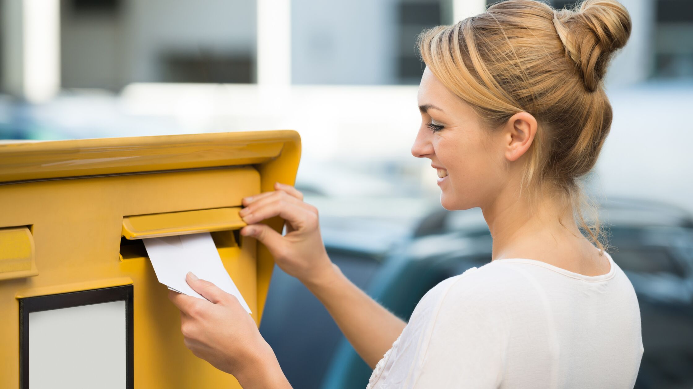 Junge Frau steckt Kündigung des Mietvertrages in den Postkasten.