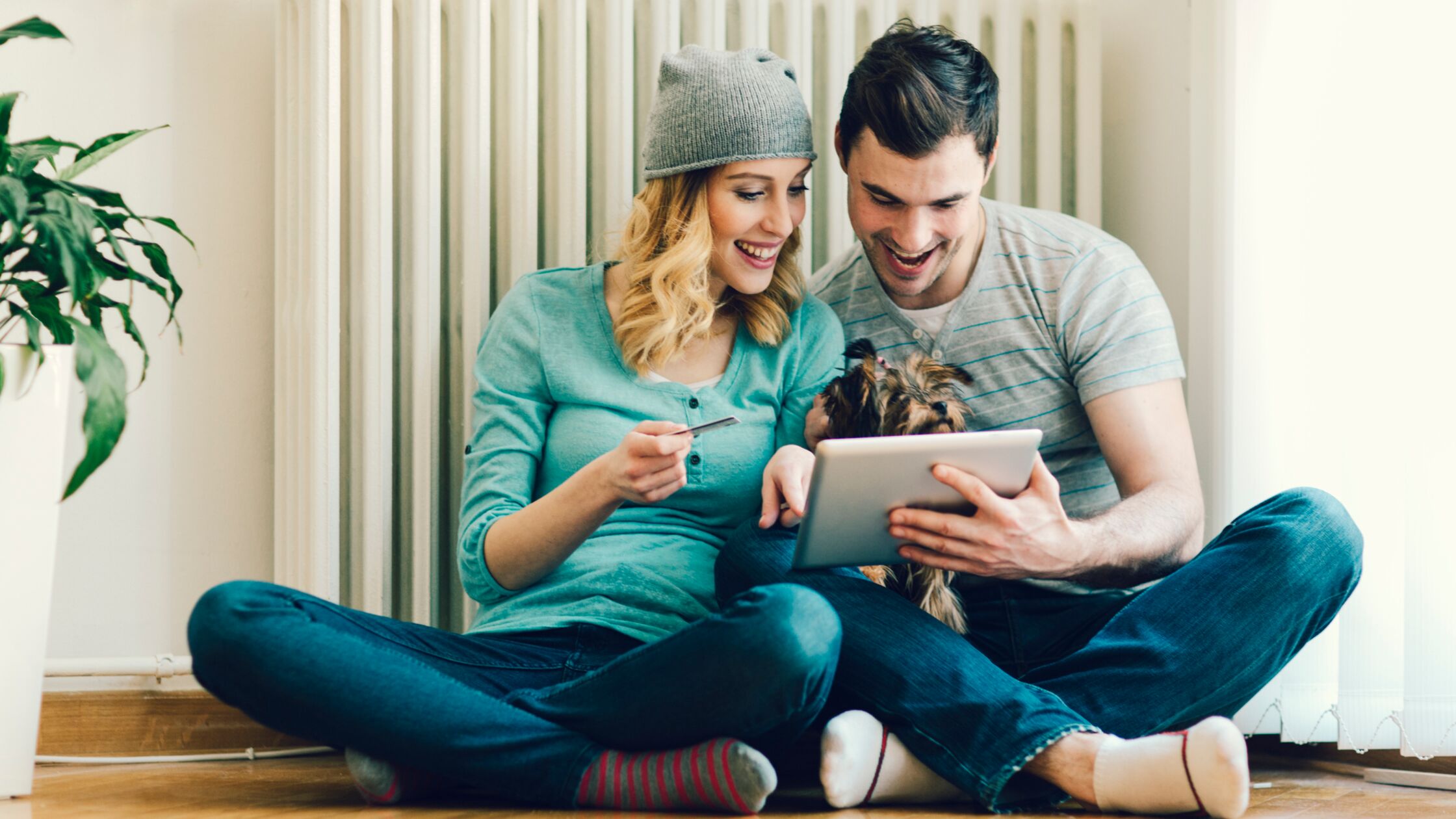 Gasanbieter wechseln: Tipps zu Kündigung und Preisvergleich Junges Paar sitzt mit Tablet-PC vor einem Heizkörper