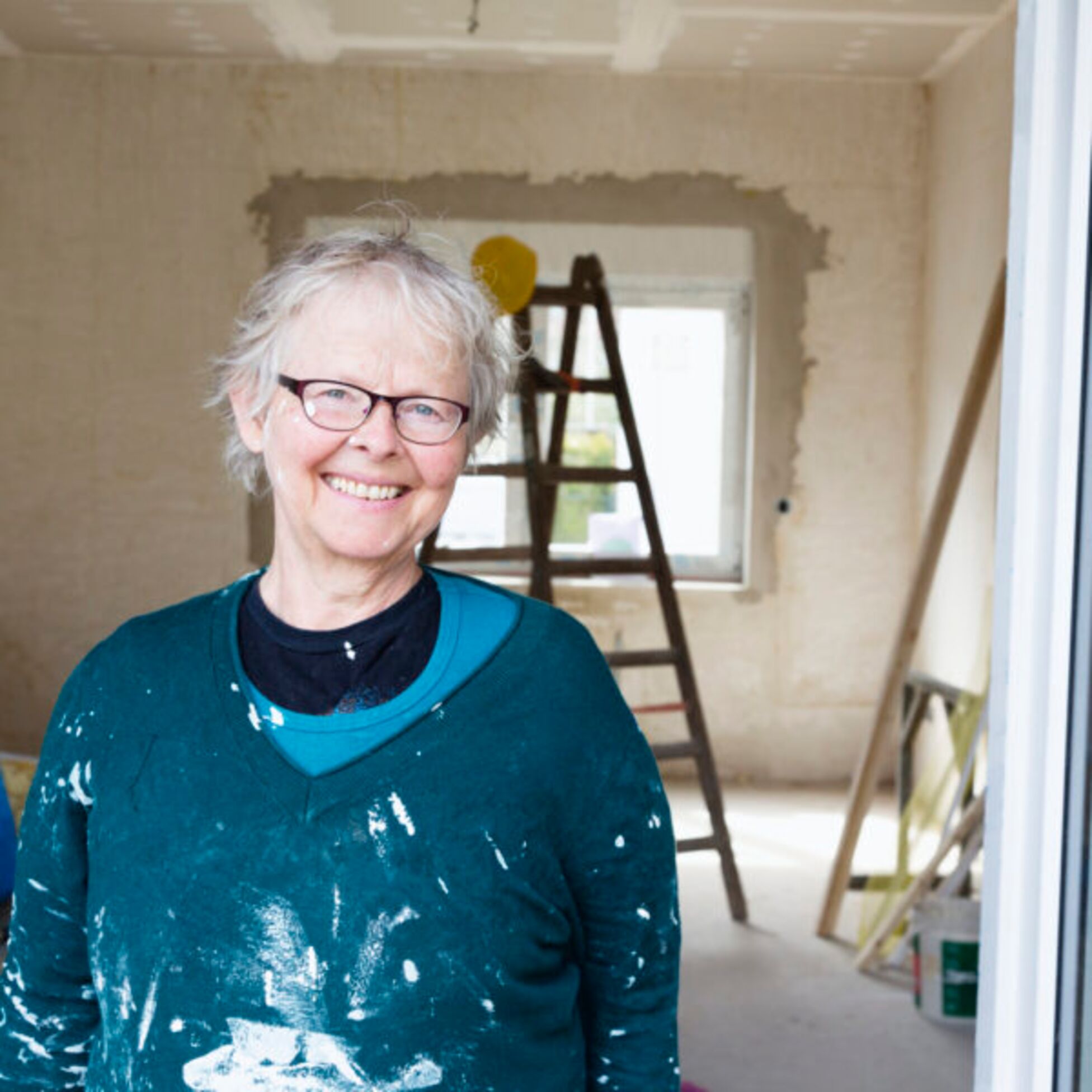 Ältere Frau renoviert fröhlich eine Wohnung