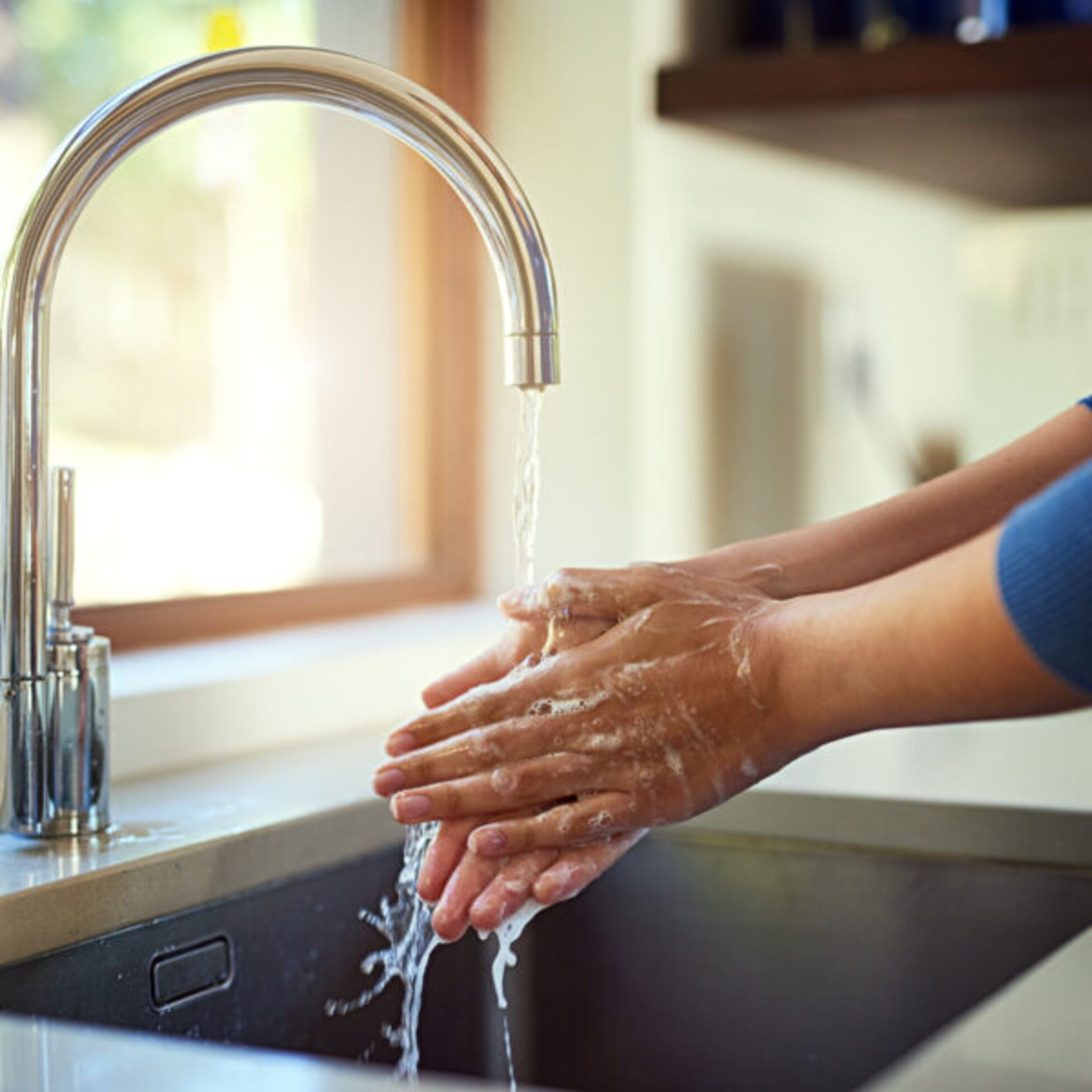 Frau wascht Hände unter Wasserhahn