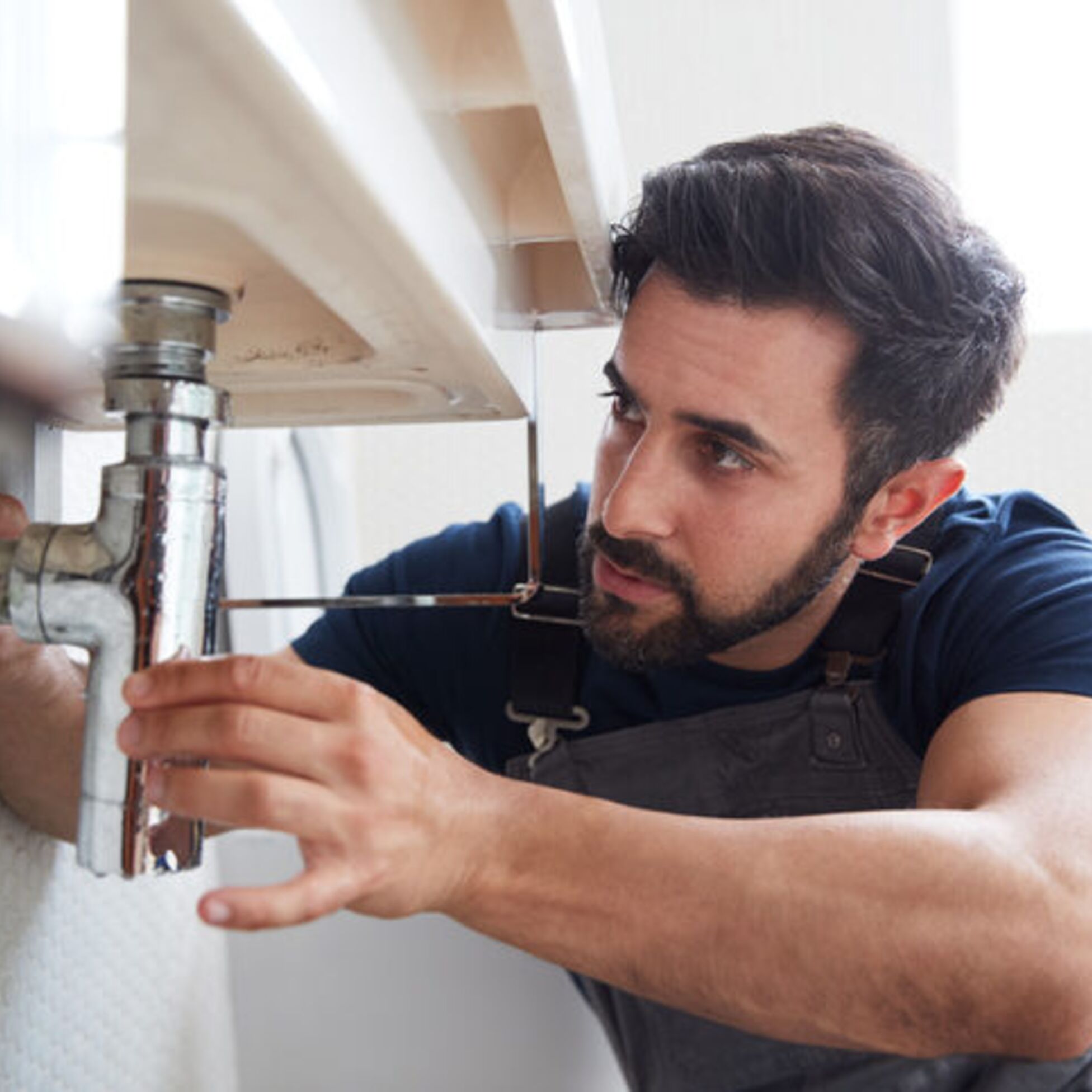 Hausmeister repariert ein Abflussrohr im Badezimmer