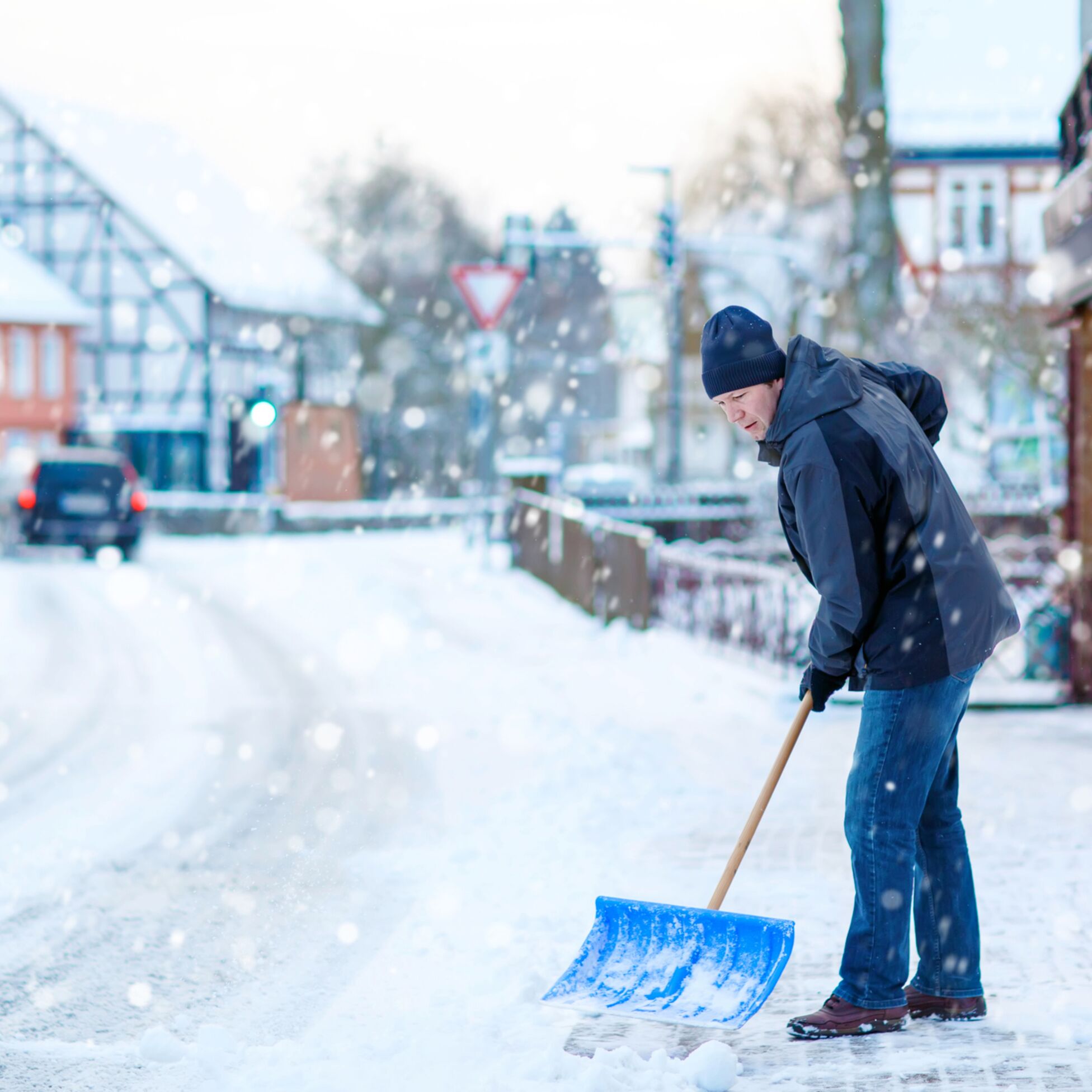 Mann räumt Schnee im Winter mit Schaufel