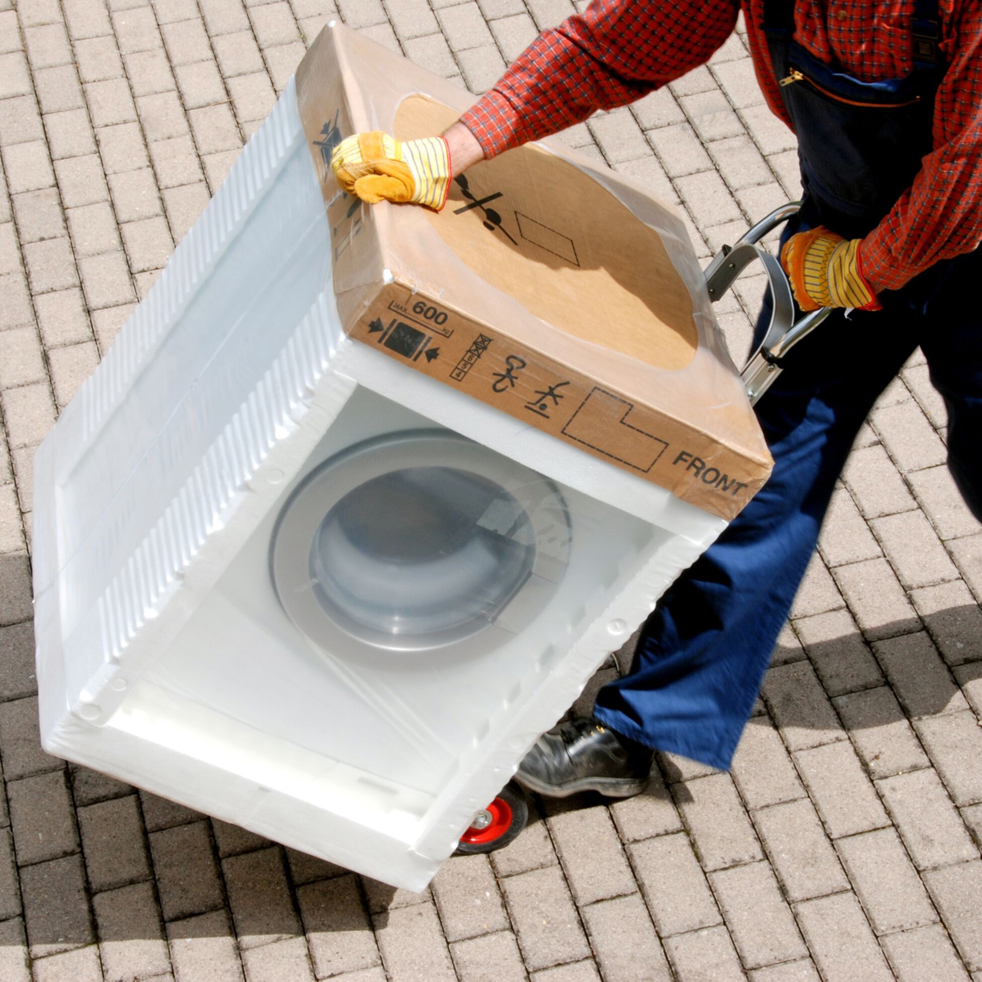 Mann transportiert Waschmaschine bei Umzug auf Sackkarre