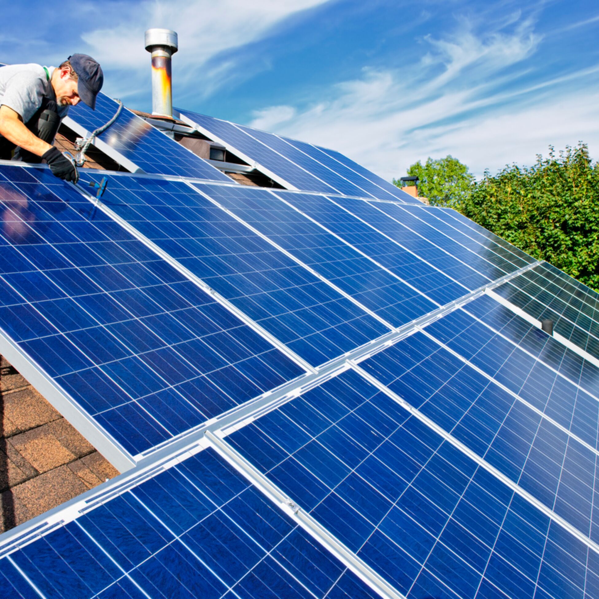 Mann installiert Solaranlage auf Hausdach