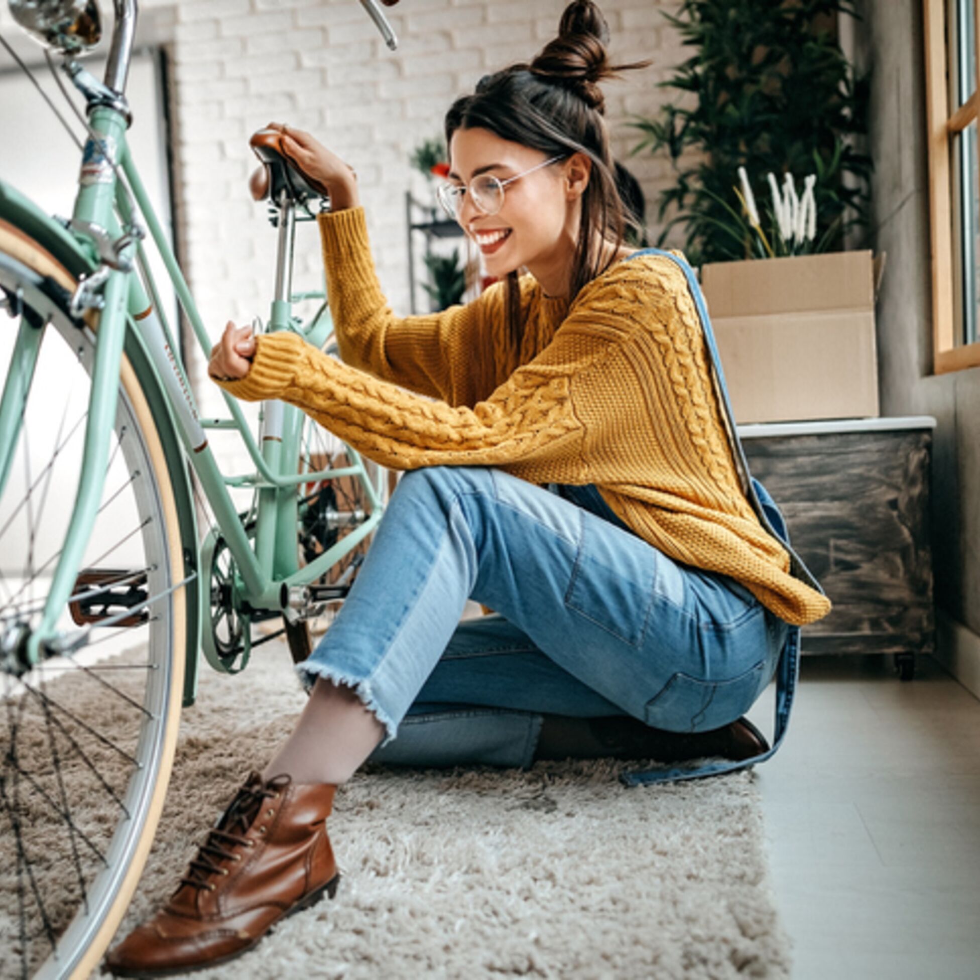 Junge Frau mit Fahrrad in neuer Wohnung